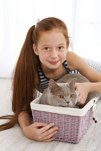 漂亮的小女孩，和在房间里的篮子里的猫