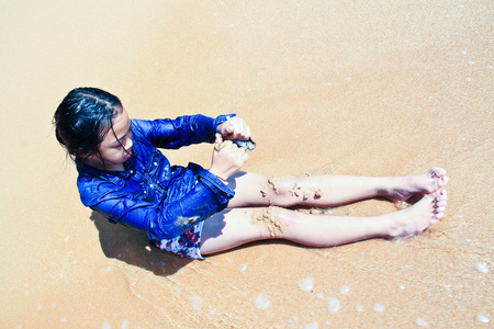 年轻的姑娘在海滩上玩沙子
