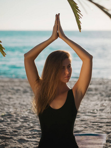 美丽的年轻女子，荷花姿势上树棕榈树与热带海滩早上瑜伽练习
