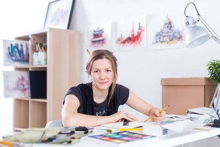 年轻的女艺术家素描写生用铅笔在她在工作室工作的场所。灵感画家侧面视图肖像