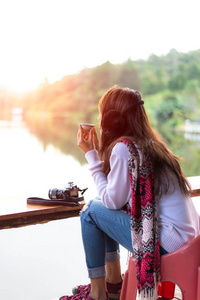 年轻女子的手冷和早上的天捧着杯茶。旅游概念