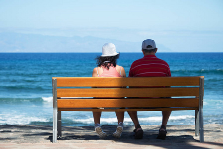 老年人对夫妇坐在海边的长椅上