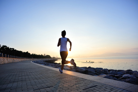 运行在海边的跑步运动员。女人健身剪影日出慢跑锻炼健康概念