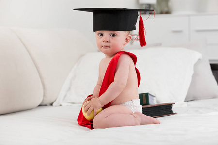 可爱的男婴，毕业帽拿着苹果。宝贝 e 的概念