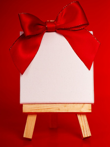 与空白画布上圣诞红色背景的木制画架