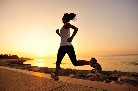 运行在海边的跑步运动员.女人健身剪影日出慢跑锻炼健康概念照片