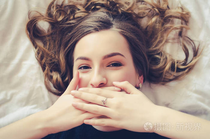 笑着十几岁的女孩捂着嘴,用她的双手