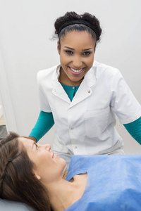 微笑着站在女性患者接受 x 线扫描的医生