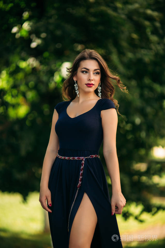 一个漂亮的女孩穿着蓝色的衣服在公园散步