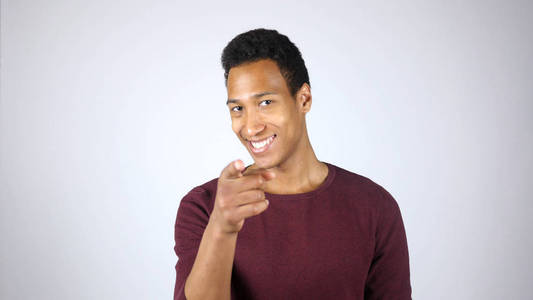 微笑的年轻黑人男子用手指向相机指点