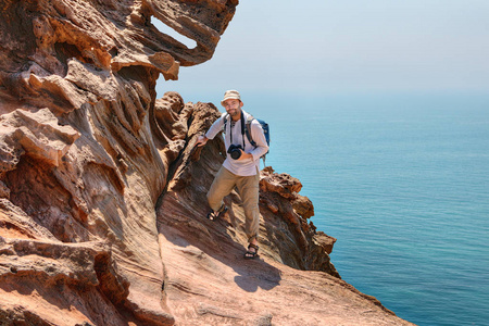 旅游摄影师爬悬崖霍尔木兹岛的海面，