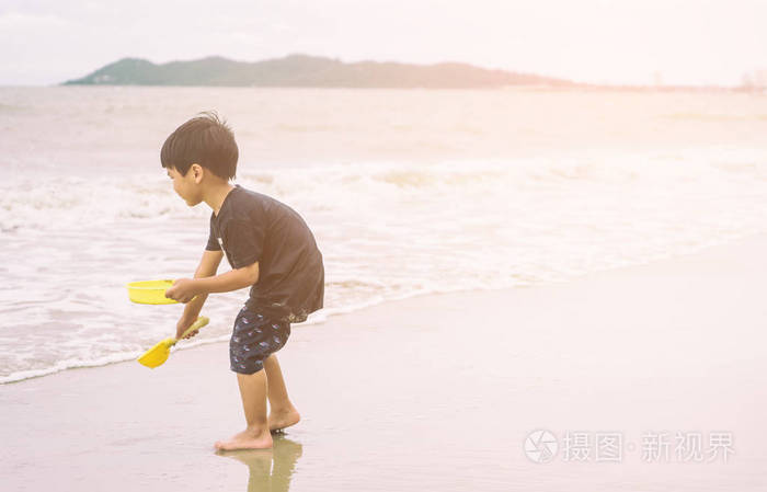 小男孩在玩沙子和海滩上的浪