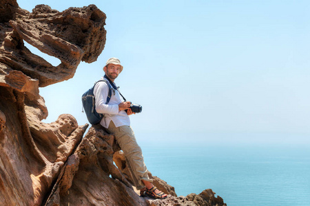 摄影师坐在一块岩石上旅行，霍尔木兹岛，伊朗时