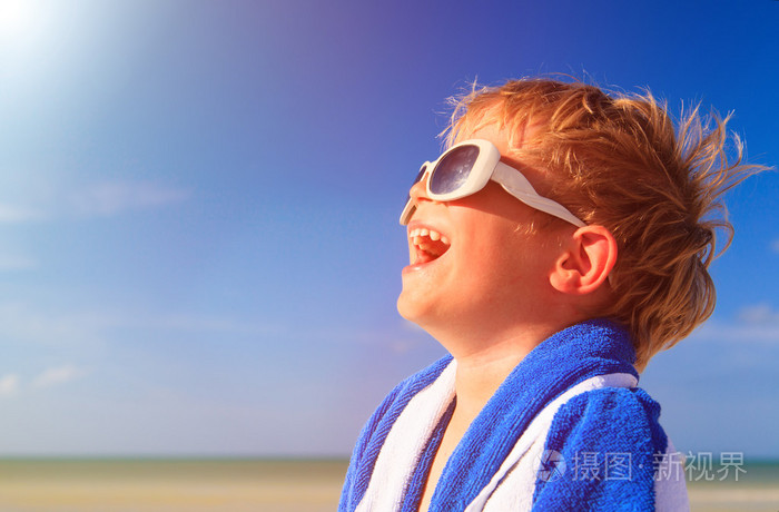快乐的小男孩笑裹在沙滩巾上天空
