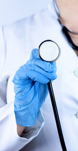 医生在蓝色手套手里显示黑色听诊器，在白色的背景