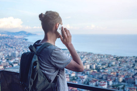 带背包的男子旅行者在城市的背景电话交谈