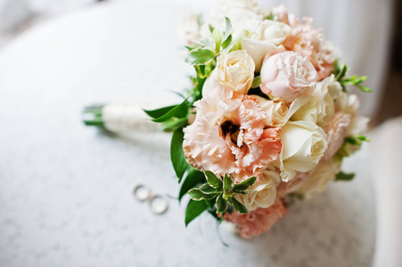 特写照片的婚礼花束和躺在桌子上的戒指