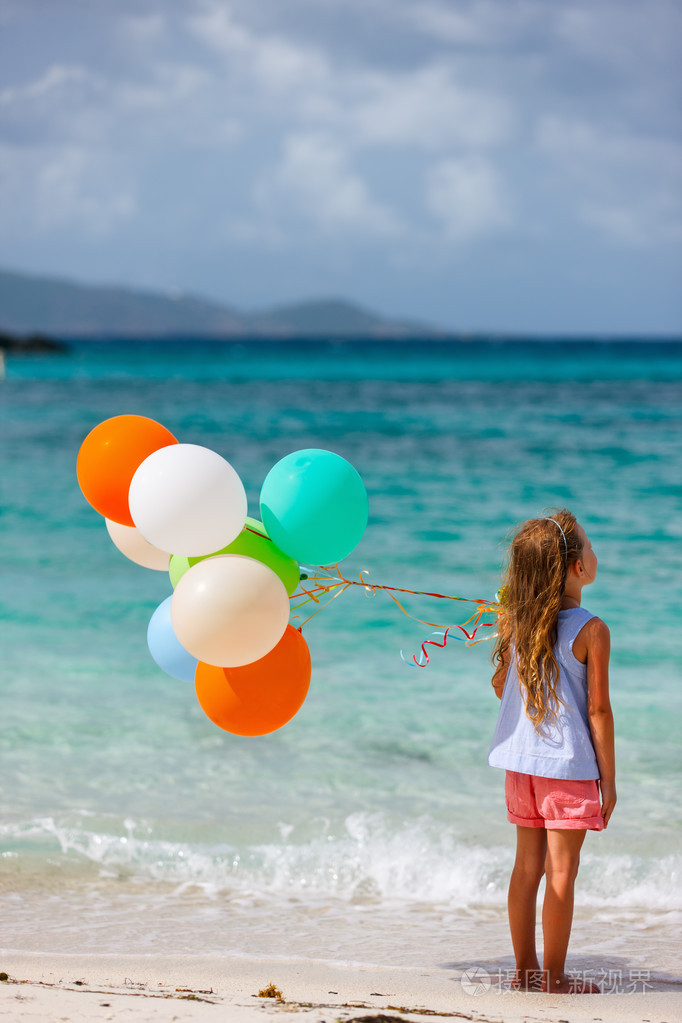 小女孩与气球在海滩后面观