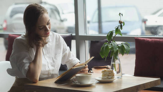 阅读本书和放松在咖啡馆里的女孩。在午休时休息的业务衣服的女孩