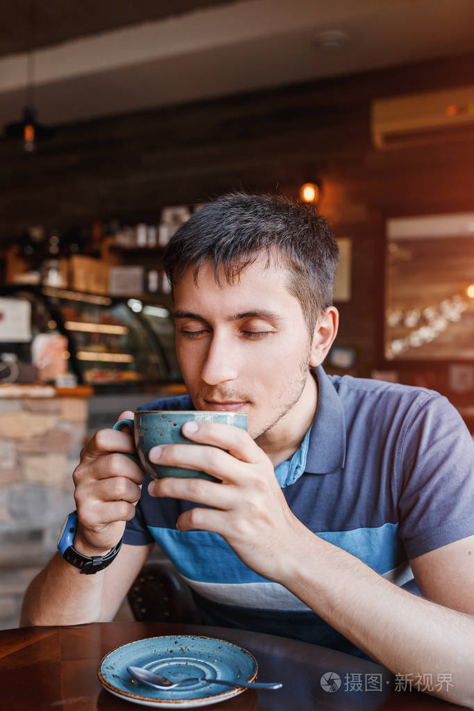 一名年轻男子喝香浓的咖啡,在咖啡馆或餐厅