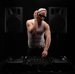 穿白衬衣的男人 dj dj 混音器上播放音乐.工作室拍摄.黑暗的背景照片