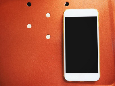 白色智能手机在金属橙色背景下的关闭视图