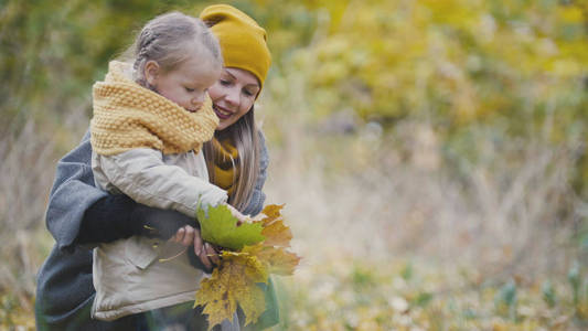 妈妈和女儿在公园玩的秋天黄叶