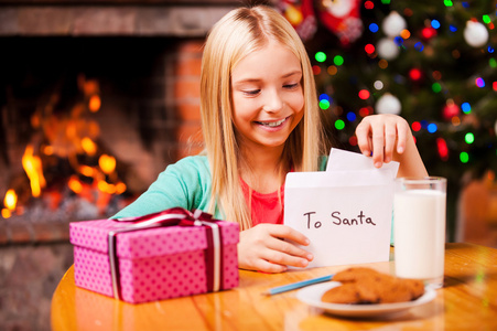 把信给圣诞老人放进信封里的小女孩