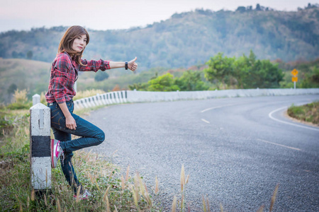 旅游搭便车的女人站在山上的道路上