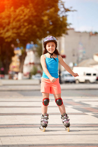 可爱的小女孩，在美丽的夏日城市滑板公园溜冰学习