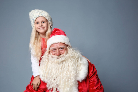 可爱的小女孩与圣诞老人反对颜色背景