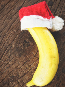 在木桌上的圣诞节帽子香蕉顶部视图
