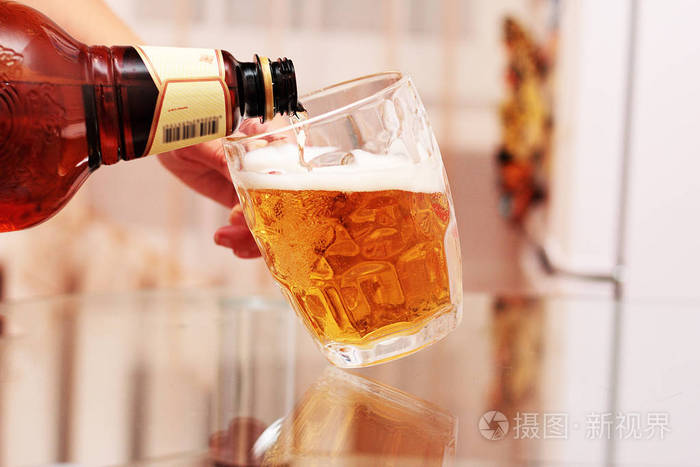 一个女人将啤酒倒入一个玻璃杯子