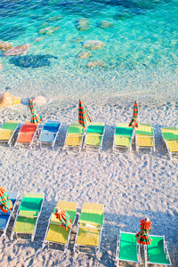 日光浴浴床和遮阳伞在美丽的欧洲海滨，在意大利的蒙泰罗索