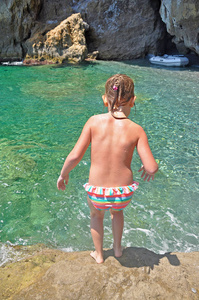那女孩要从石头在绿色的海洋潜水
