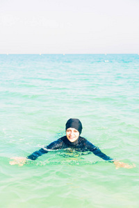 Burkini 在海里游泳的年轻女子