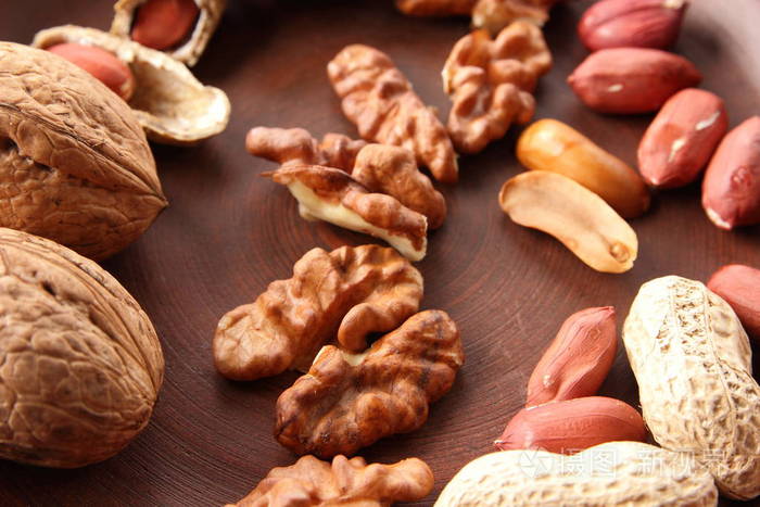 核桃和花生在白色背景上的褐色粘土板上