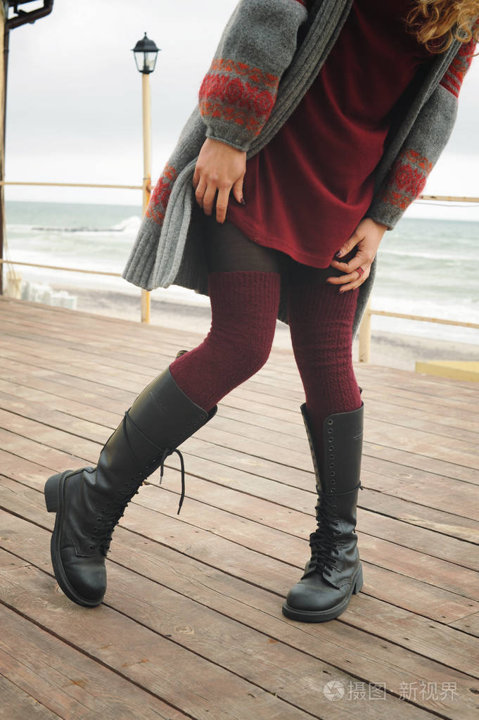 女性的双腿苗条穿着膝盖高靴子的鞋带和针织的袜子