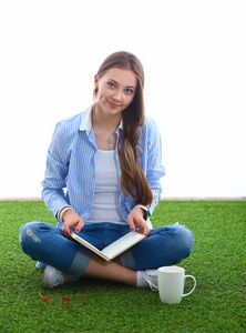 年轻女子坐在一起在草地上的书