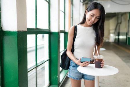 女人享受冰的咖啡和拿着手机