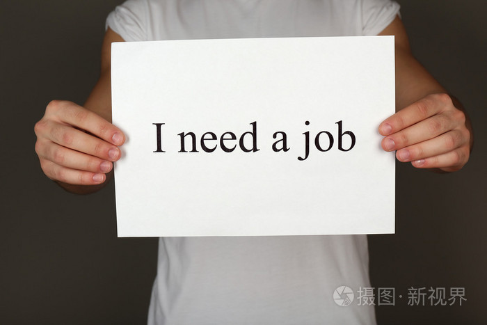 表纸上题字我需要一份工作在男性手上黑暗的背景