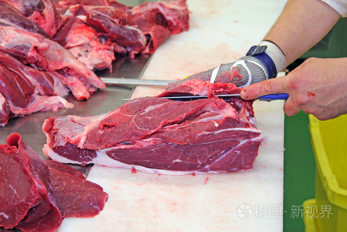 切割一块新鲜的牛肉肉的屠夫