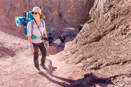 年轻女子背包旅游的立石沙漠峡谷踪迹