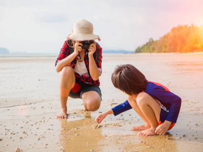 度假夏秋旅游概念。漂亮的女人，拍摄她的孩子在热带海滩