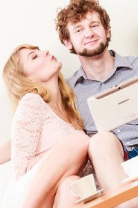 女人女孩亲吻男人家伙的平板电脑。乐趣