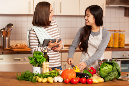 两个微笑的女性朋友在家里做饭在一起照片