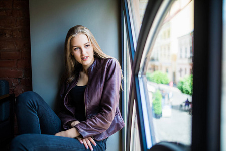年轻女子坐在窗台上的一家咖啡馆和享受的自由时间