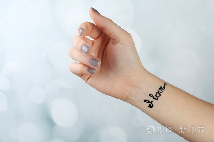 女性手臂纹身在明亮的背景上照片-正版商用图片0v7z96-摄图新视界
