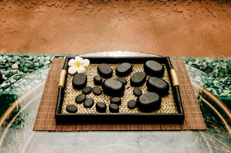 传统泰国著名禅 spa 仪式石头上柳条托盘与莲花木藤玻璃桌上与抽象瀑布墙上背景。水疗按摩和健康的生活方式的概念