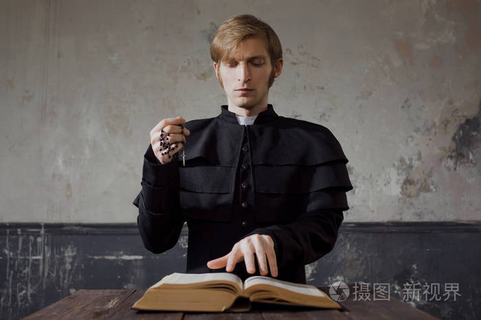 向上帝祈祷的英俊年轻的天主教神父的肖像